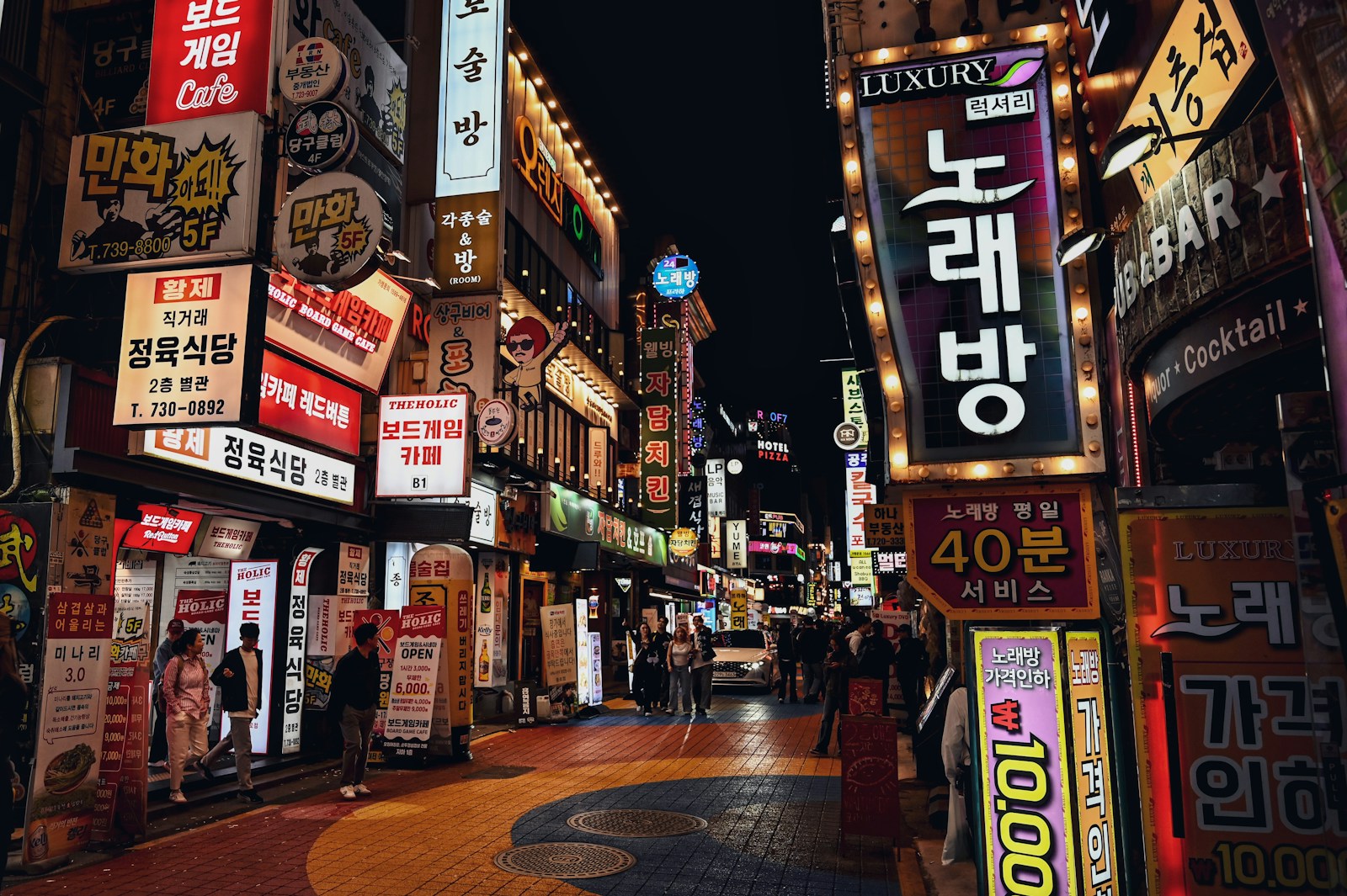 네온 간판이 불을 밝힌 밤거리를 걷는 사람들