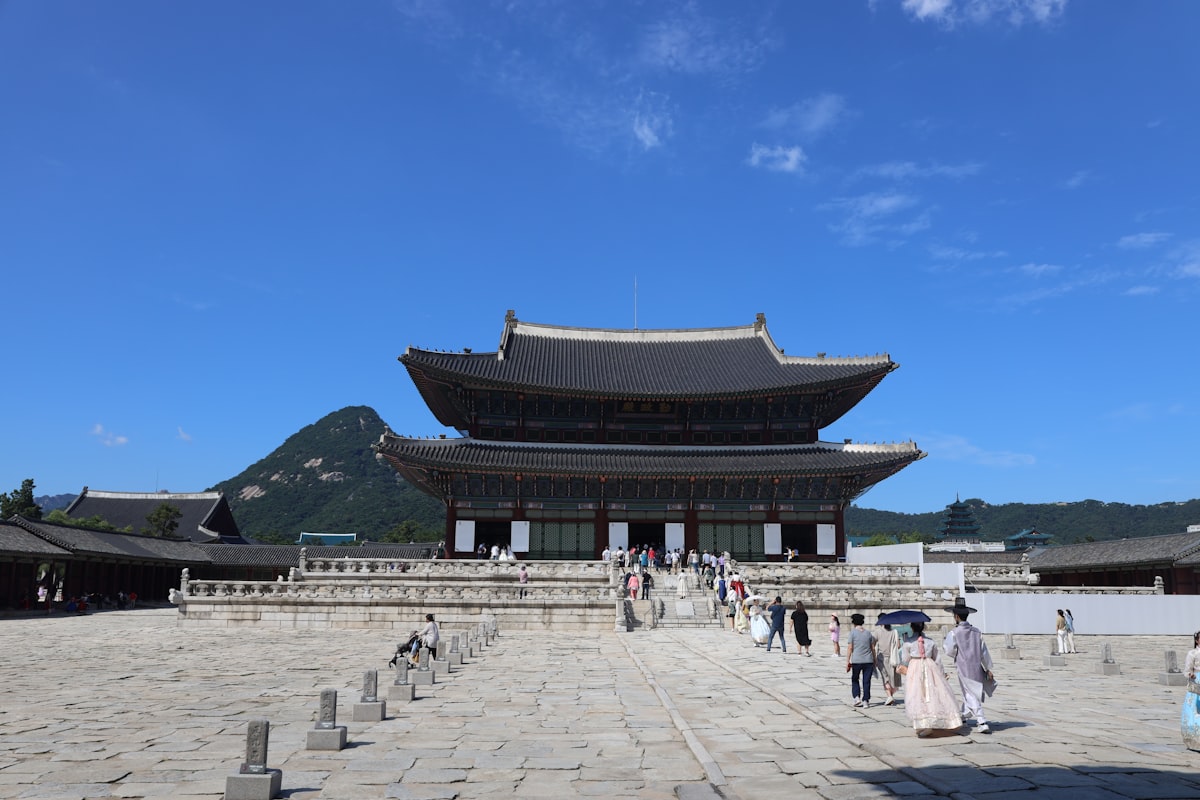 한복을 입은 관람객들이 경복궁 근정전 앞 넓은 돌마당을 걸어가고 있다